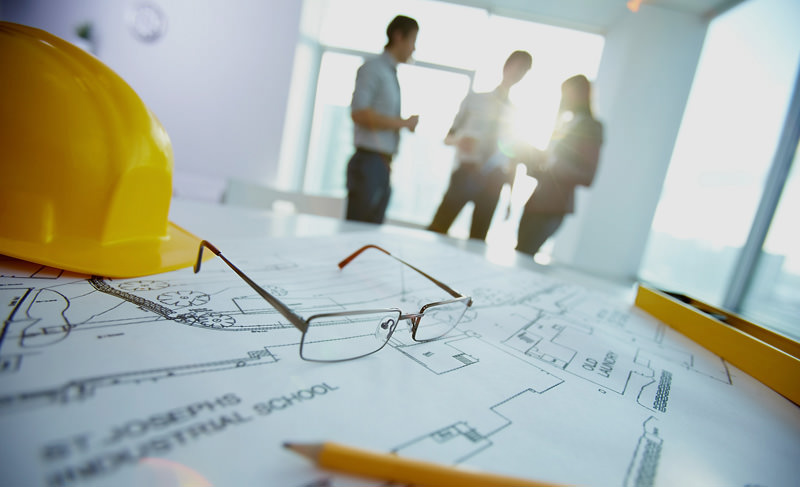 Hardhat en bouwtekeningen op een planningstafel bij CCM