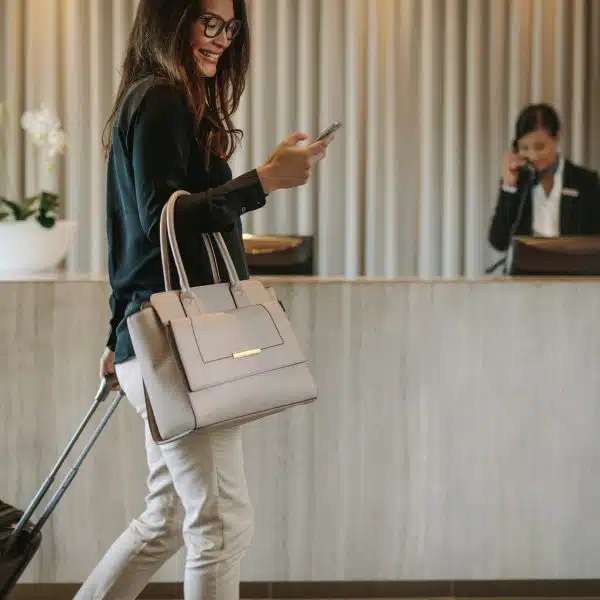 Traveller using a mobile phone while pulling a suitcase
