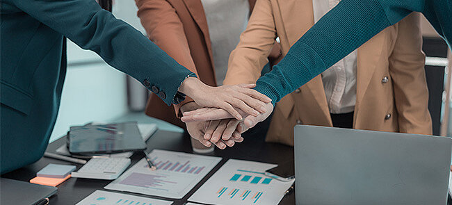 Zakelijk team dat handen op elkaar legt, symbool voor teamwork
