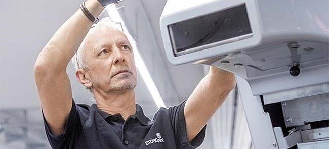 Man met een accuschroevendraaier werkt aan een grijze machine